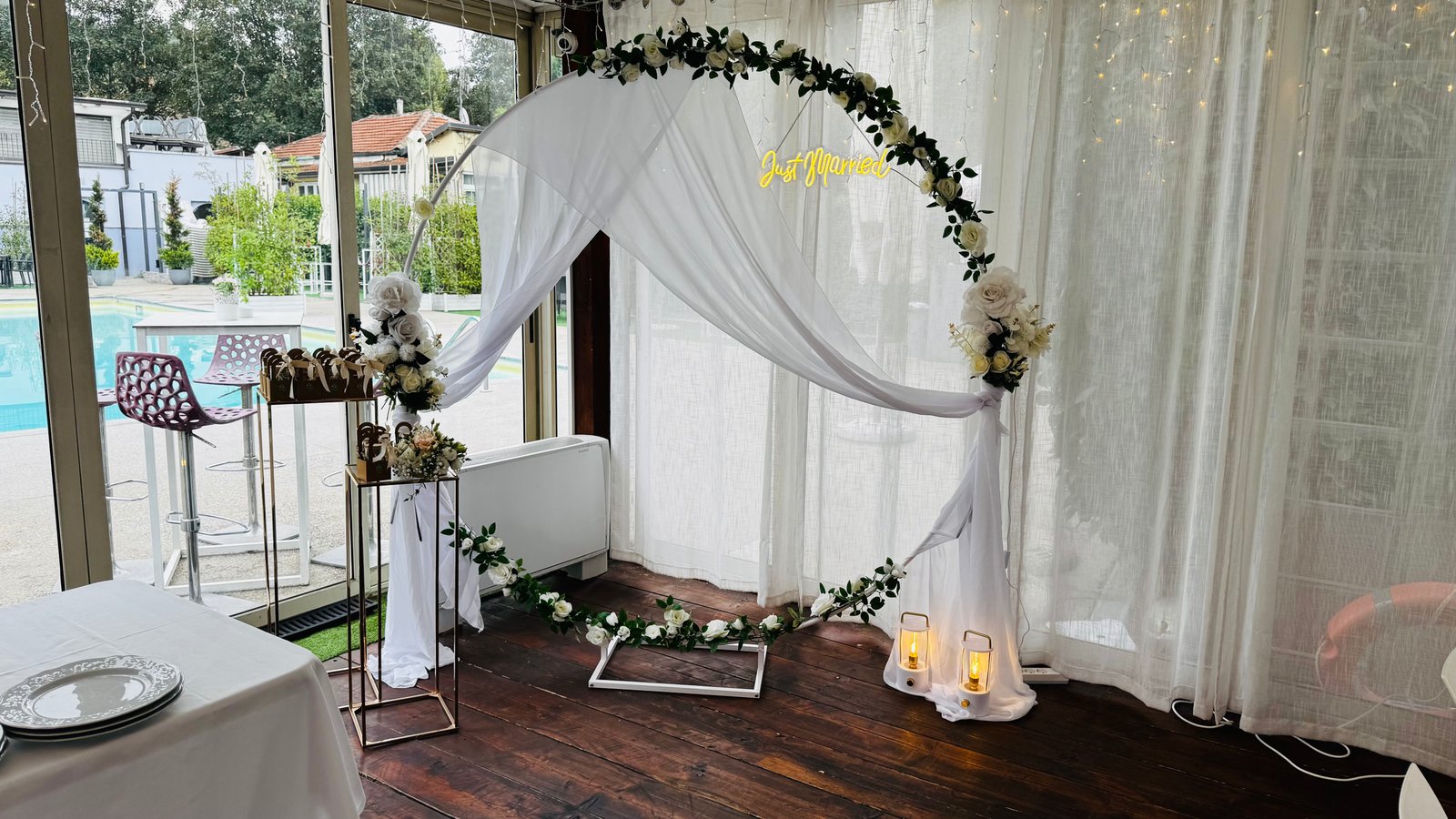 Allestimento con arco floreale, drappeggi bianchi e insegna neon Just Married
