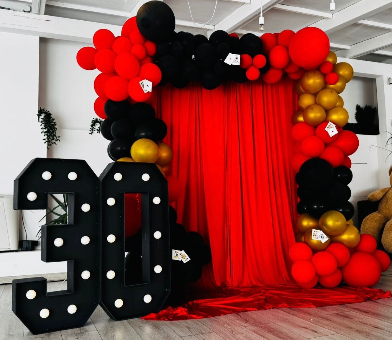 30esimo compleanno tema casino con palloncini rossi, neri e oro, tenda rossa e numeri luminosi 30