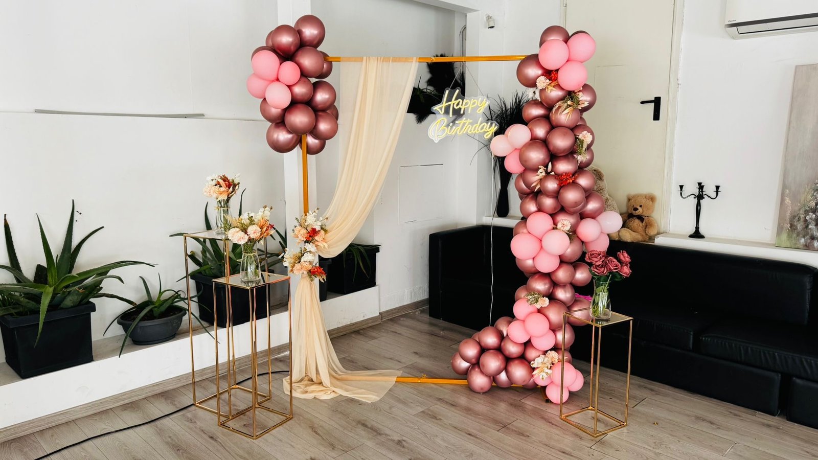 Allestimento compleanno con palloncini rose gold e rosa su struttura dorata, neon Happy Birthday e fiori