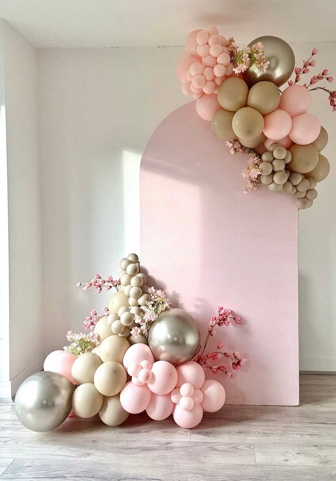 Allestimento con arco rosa, palloncini salvia, crema e argento con fiori di ciliegio