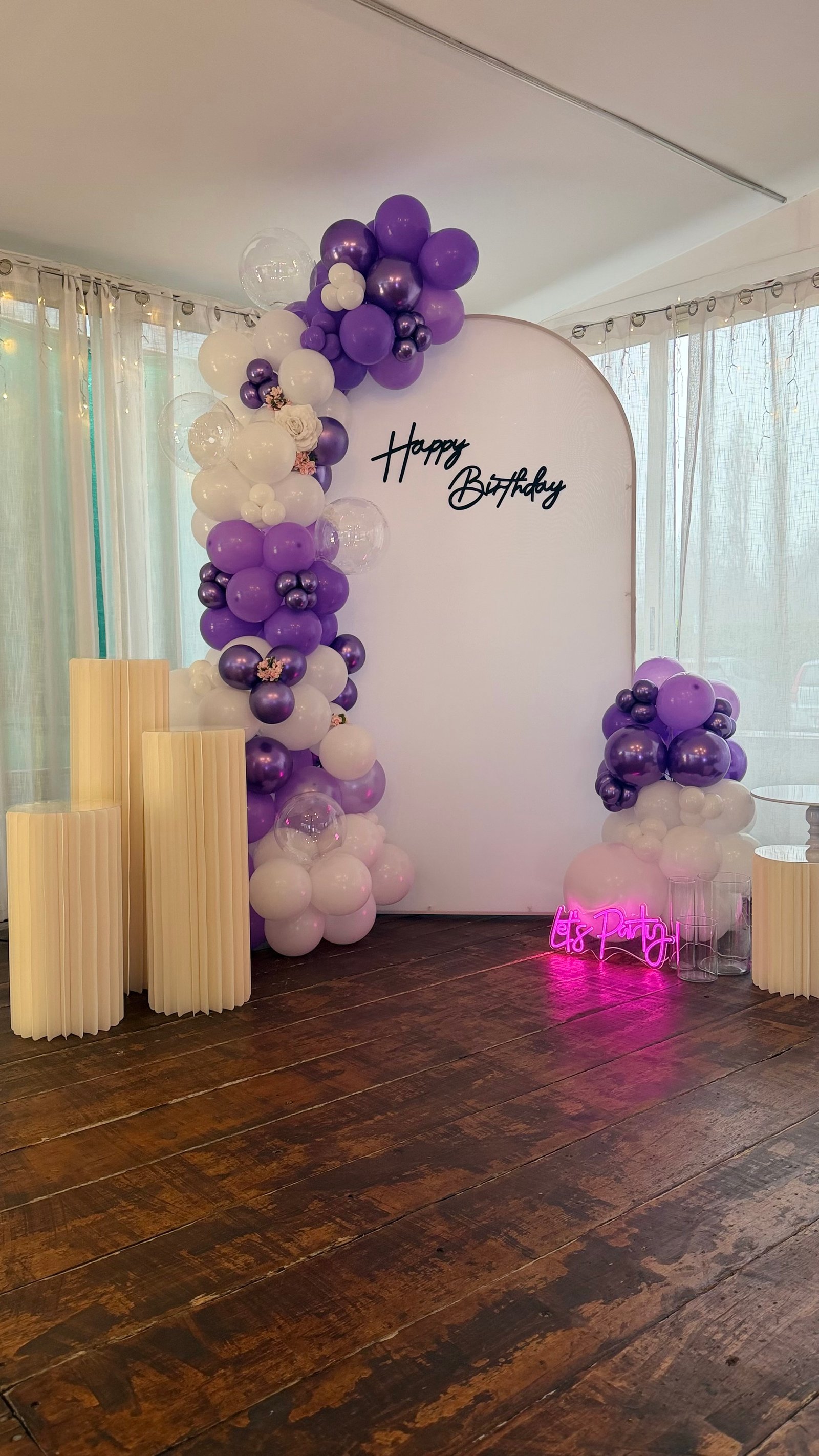 Compleanno con arco palloncini viola e bianchi, scritta Happy Birthday e neon Let's Party